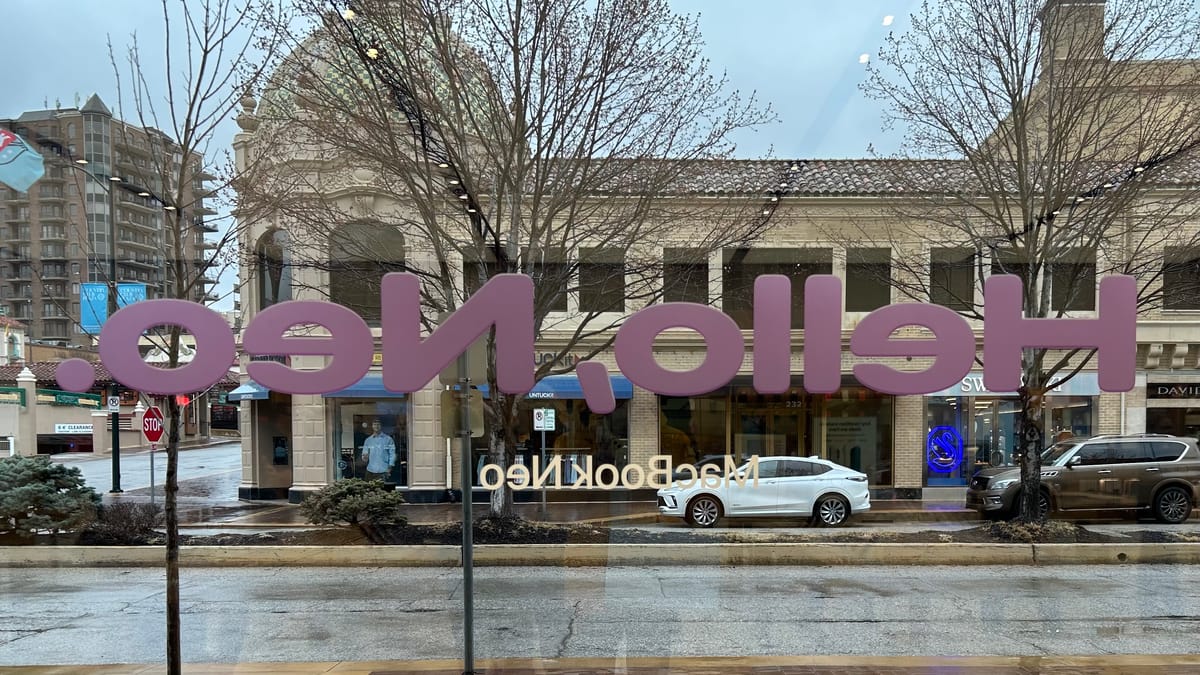 A rainy shopping district seen through glass with "Hello, Neo" seen in reverse.